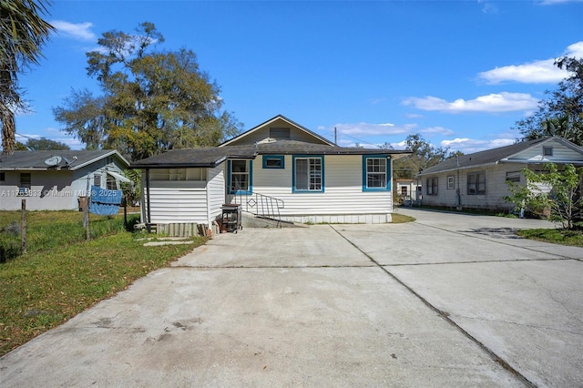 bungalow with entry steps, concrete driveway, a front yard, and fence