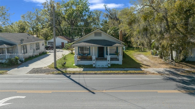 bungalow-style house with a porch, a shingled roof, and a front yard