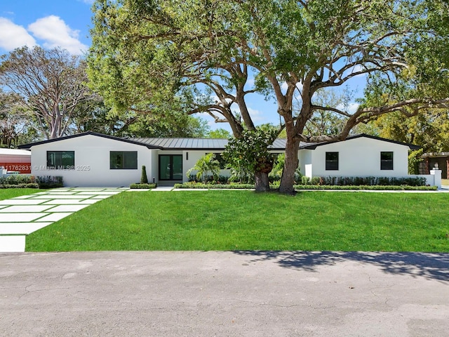 view of front facade featuring a standing seam roof, stucco siding, french doors, and a front yard