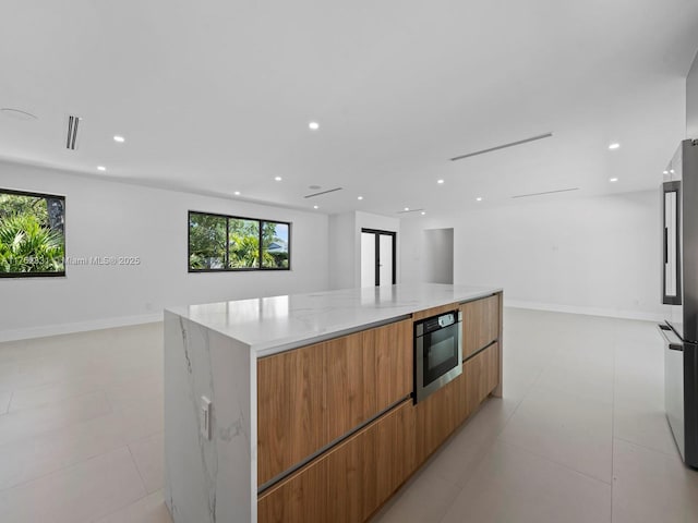 kitchen with a spacious island, recessed lighting, built in microwave, modern cabinets, and open floor plan