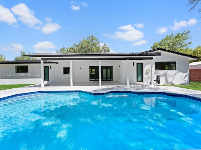 rear view of house with a patio area, stucco siding, and an outdoor pool