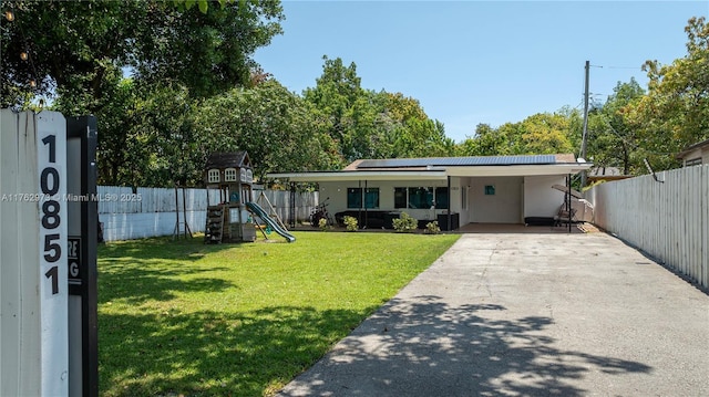 view of front of house featuring a fenced backyard, a playground, concrete driveway, a front yard, and a carport