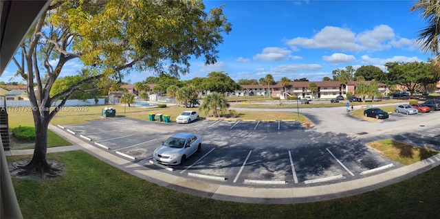 surrounding community with uncovered parking, a residential view, and a lawn