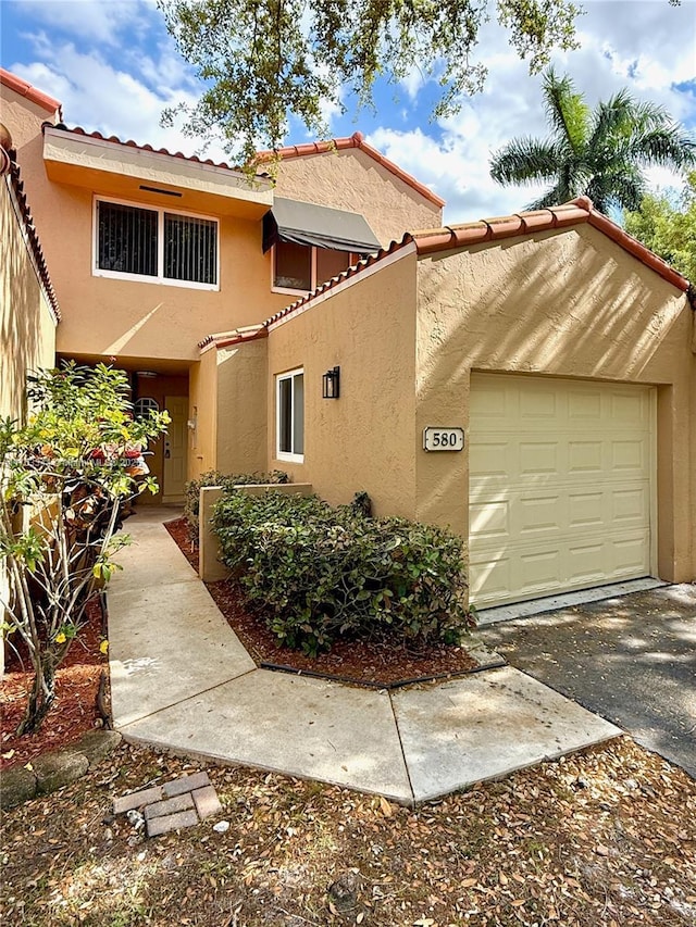 view of property exterior with stucco siding, an attached garage, and a tile roof