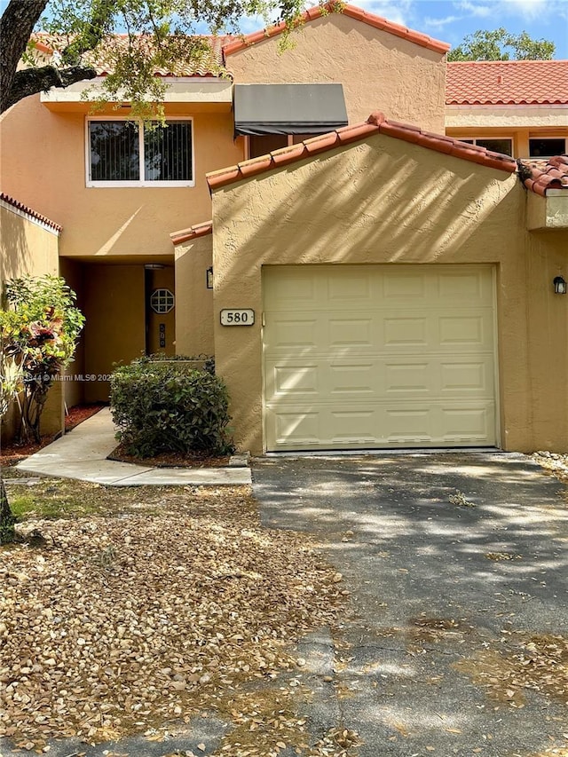 view of front of property featuring a tiled roof, an attached garage, and stucco siding