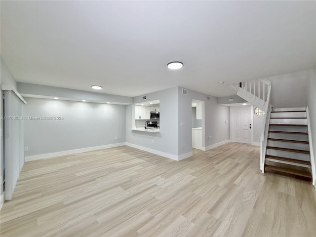 unfurnished living room with light wood finished floors, stairway, visible vents, and baseboards