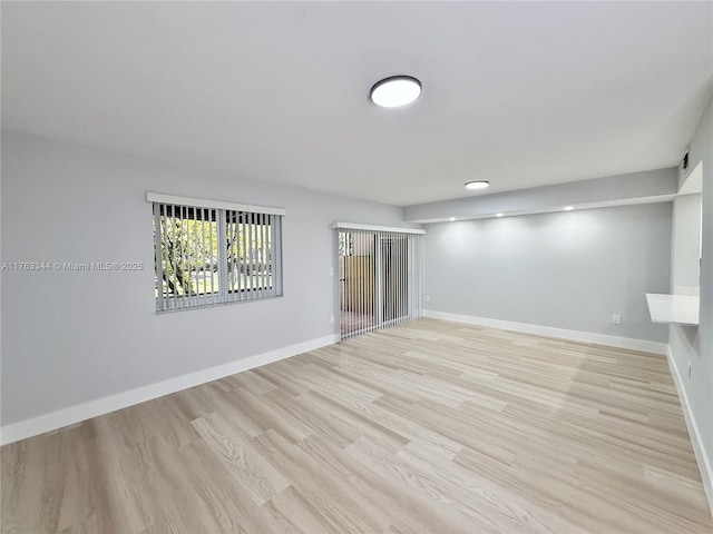 spare room with light wood-type flooring and baseboards