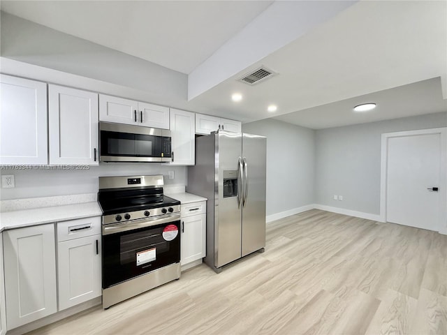 kitchen with visible vents, baseboards, light wood-type flooring, appliances with stainless steel finishes, and white cabinetry