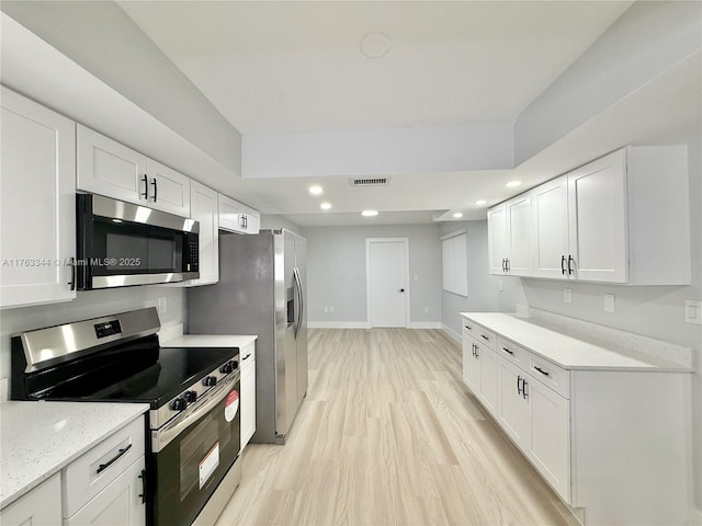 kitchen with baseboards, recessed lighting, light wood-style flooring, appliances with stainless steel finishes, and white cabinetry