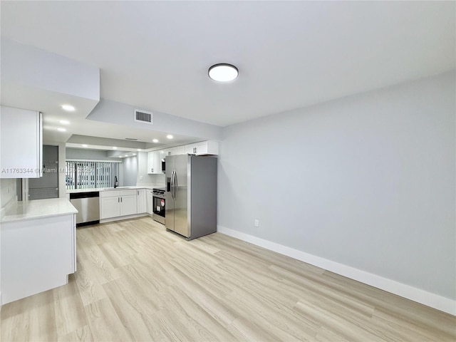 kitchen with baseboards, visible vents, stainless steel appliances, white cabinets, and light wood-type flooring