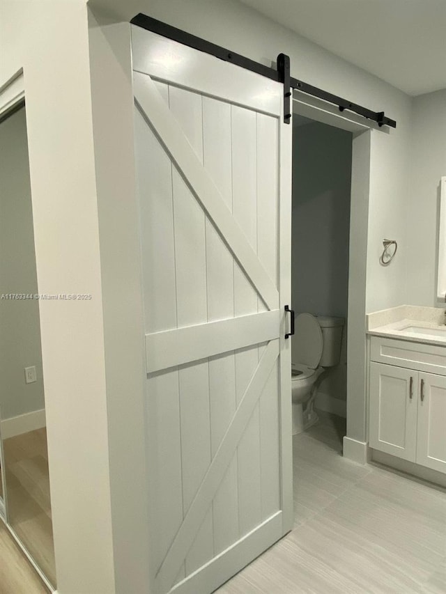 bathroom featuring toilet, vanity, and baseboards