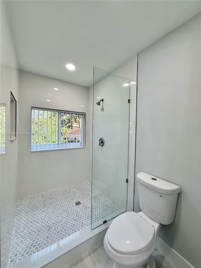 full bathroom with tile patterned floors, toilet, and a tile shower