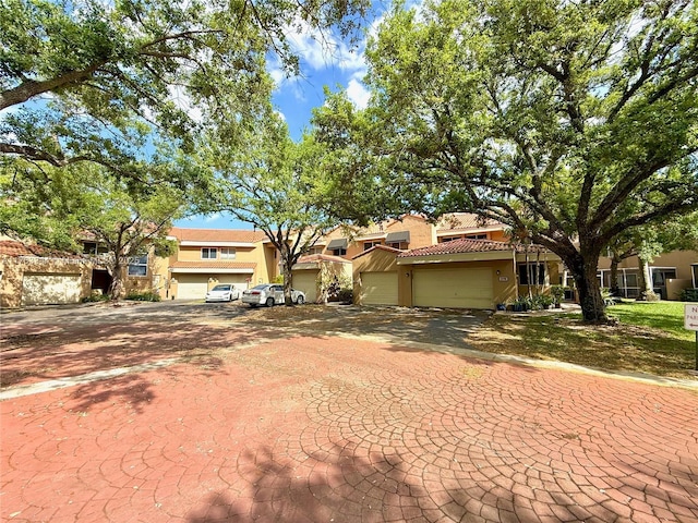 view of front facade with stucco siding, an attached garage, driveway, and a tile roof