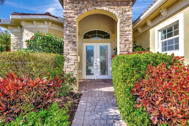 property entrance with french doors, stone siding, and stucco siding