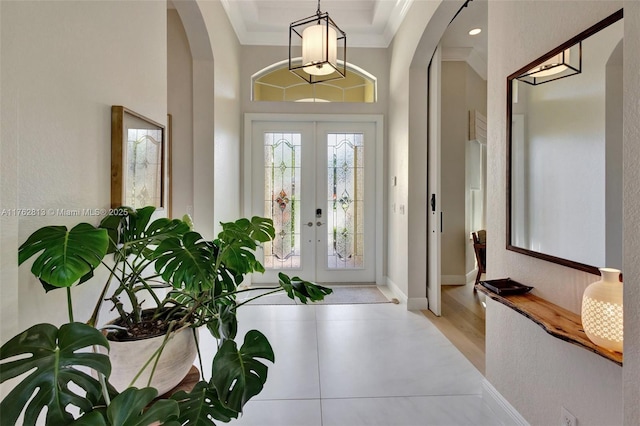 foyer entrance featuring french doors, arched walkways, baseboards, and ornamental molding