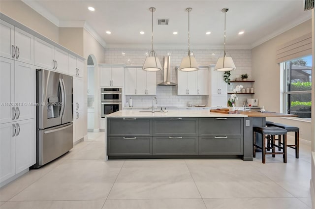 kitchen featuring gray cabinets, stainless steel appliances, white cabinets, wall chimney exhaust hood, and tasteful backsplash