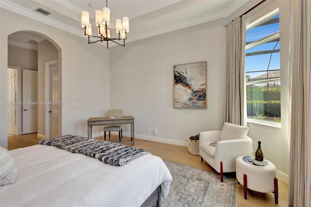 bedroom with a raised ceiling, visible vents, arched walkways, and baseboards