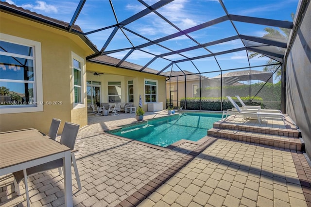 outdoor pool with glass enclosure, outdoor dining space, a ceiling fan, and a patio area