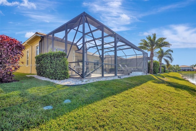 exterior space featuring stucco siding, a yard, and glass enclosure