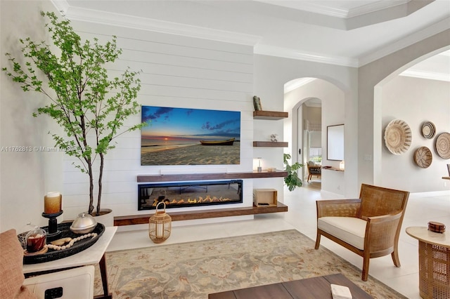 living room with arched walkways, a glass covered fireplace, tile patterned floors, and ornamental molding