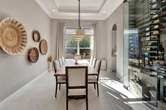 dining area featuring light tile patterned floors, baseboards, a tray ceiling, arched walkways, and ornamental molding