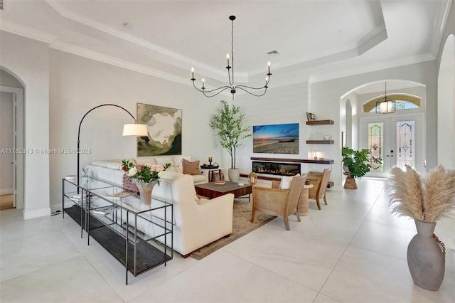 living room featuring a tray ceiling, crown molding, and arched walkways