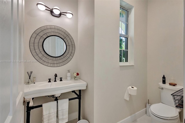 half bath with baseboards and toilet