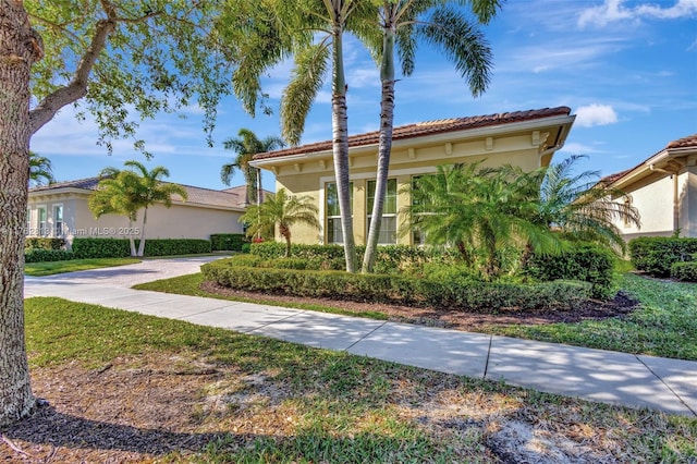 mediterranean / spanish-style home with stucco siding, a tiled roof, and driveway