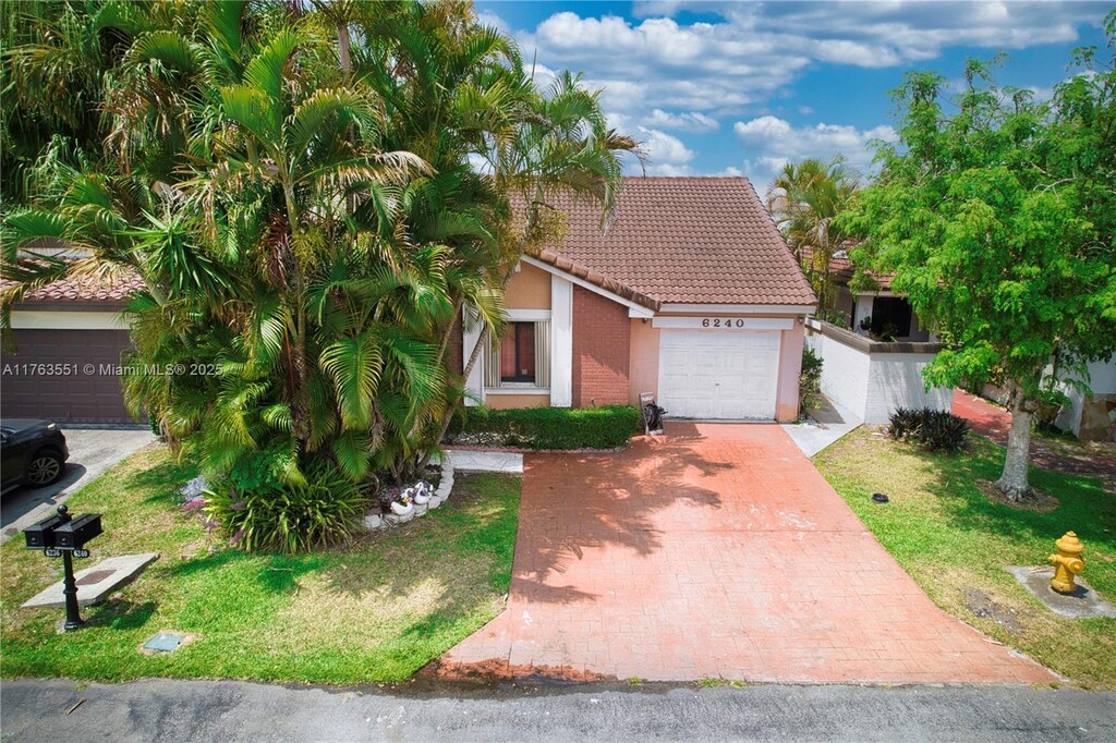 6240 NW 176th Ter, Hialeah, FL 33015 - view of front of home with a tiled roof, a front lawn, stucco siding, decorative driveway, and a garage