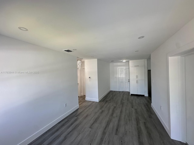 empty room featuring baseboards, visible vents, and dark wood-style flooring