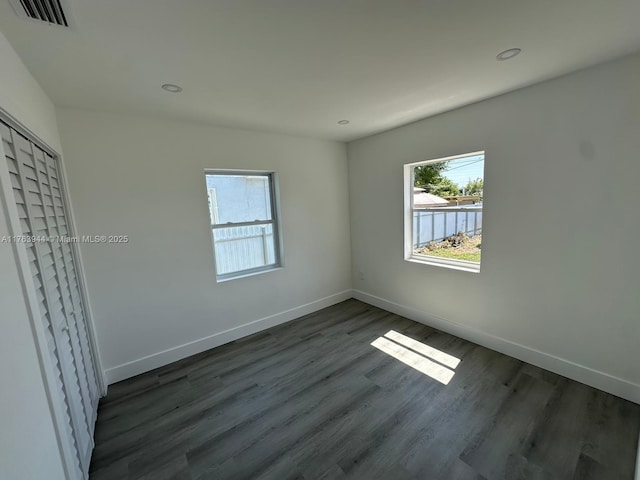 empty room with recessed lighting, visible vents, baseboards, and dark wood-style floors