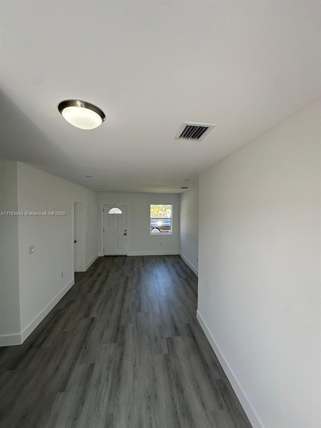 spare room featuring visible vents, baseboards, and dark wood-style floors