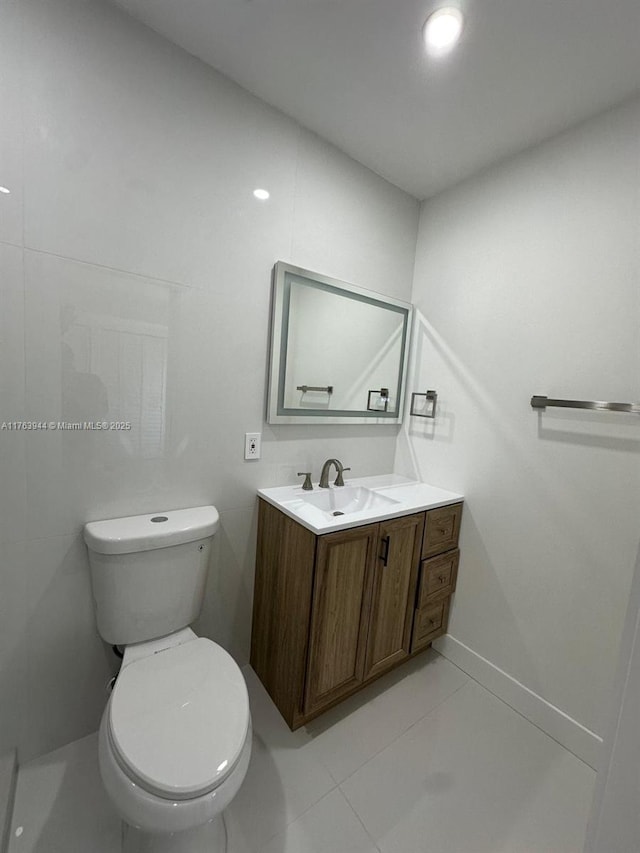 bathroom with baseboards, toilet, vanity, and tile patterned flooring