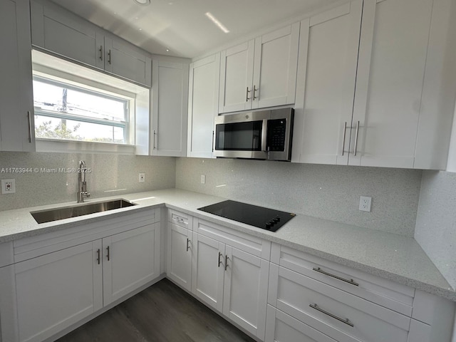 kitchen with a sink, stainless steel microwave, tasteful backsplash, and black electric cooktop