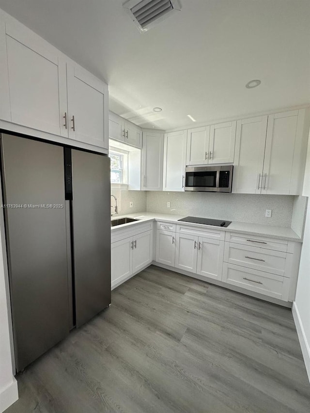 kitchen with visible vents, a sink, white cabinets, appliances with stainless steel finishes, and tasteful backsplash