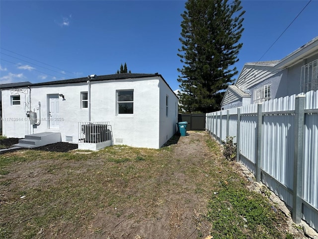 rear view of property with stucco siding, central air condition unit, and a fenced backyard