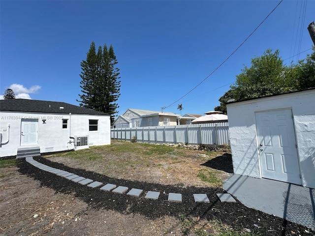 view of yard with cooling unit, an outbuilding, entry steps, and fence