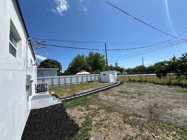 view of yard with central air condition unit, an outdoor structure, a fenced backyard, and a shed