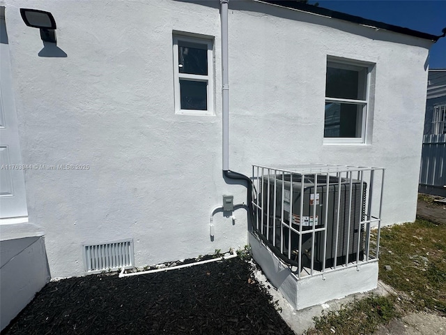 details featuring visible vents, central air condition unit, and stucco siding