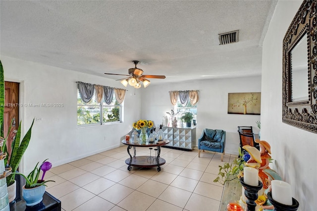 sitting room featuring light tile patterned floors, a ceiling fan, baseboards, visible vents, and a textured ceiling