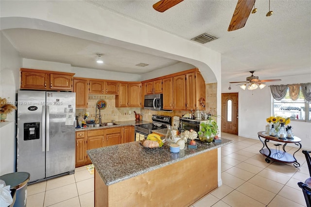 kitchen with ceiling fan, light tile patterned floors, arched walkways, and stainless steel appliances