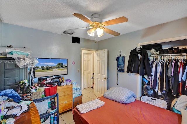 bedroom featuring ceiling fan, tile patterned floors, a closet, and a textured ceiling