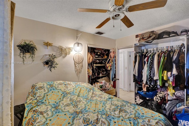 bedroom featuring tile patterned floors, visible vents, a textured ceiling, and a ceiling fan