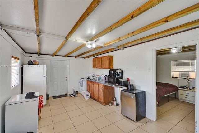 kitchen with dark countertops, beamed ceiling, light tile patterned floors, brown cabinetry, and white appliances