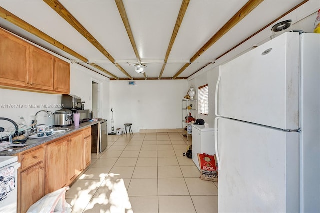 kitchen featuring beam ceiling, a sink, freestanding refrigerator, light tile patterned floors, and range