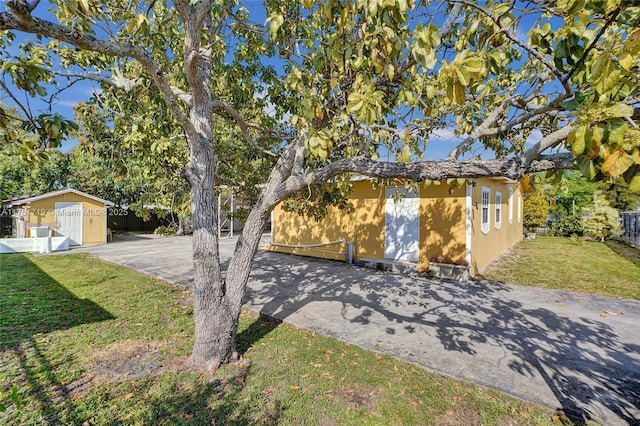 view of front of home with fence, a front yard, stucco siding, an outbuilding, and driveway