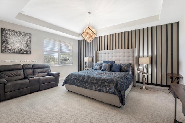 carpeted bedroom with baseboards and a raised ceiling