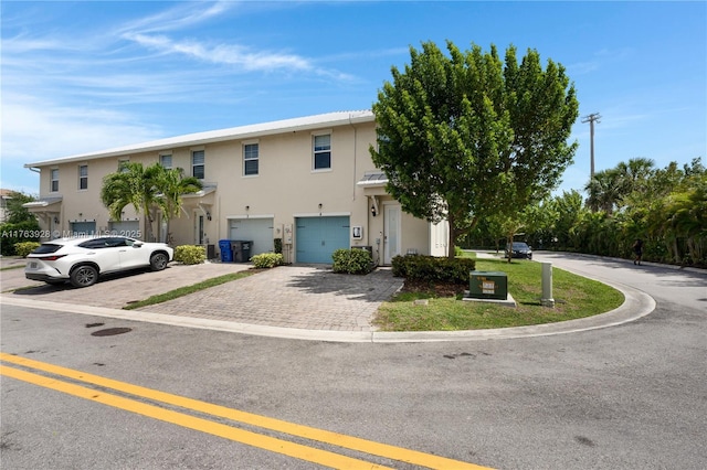 multi unit property with stucco siding, decorative driveway, and a garage