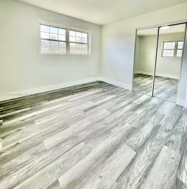 unfurnished bedroom with multiple windows, wood finished floors, and baseboards