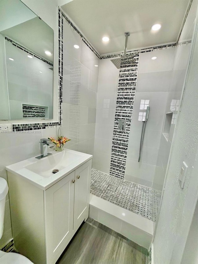 bathroom with vanity, wood finished floors, walk in shower, toilet, and backsplash